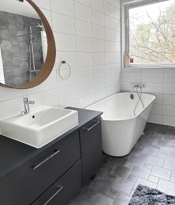 a bathroom with a sink and a tub and a mirror at The Luxurious Lakeview Villa near Stockholm in Stockholm
