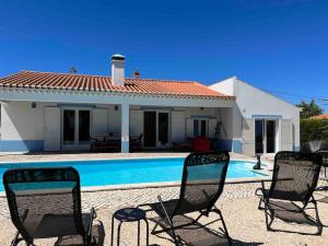 a house with a pool and two chairs in front of it at Villa Alba in Aljezur