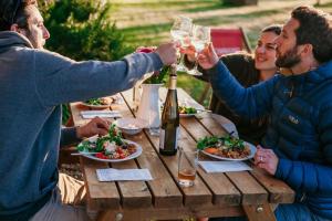 een groep mensen die rond een houten tafel wijn drinken bij Safari Tent 4 At Tapnell Farm in Yarmouth