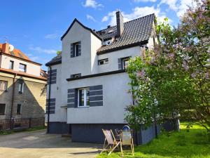 a white house with two chairs in the yard at Family Rooms in Zabrze