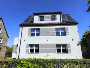 a white house with solar panels on it at Family Rooms in Zabrze