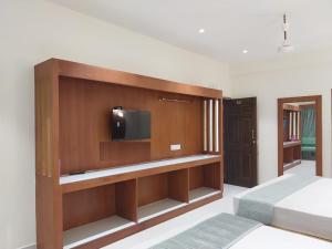 a bedroom with a bed and a tv on a wall at Hotel Harshanaa Elite in Kanyakumari