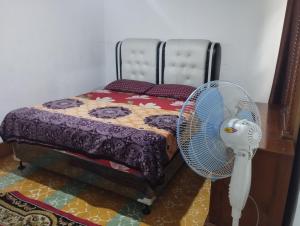 1 dormitorio con 1 cama y ventilador en el suelo en Mando Homestay II, en Bukittinggi