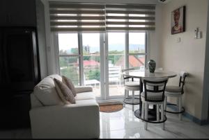 a living room with a chair and a table and a window at Chateau Apartment in New Kingston