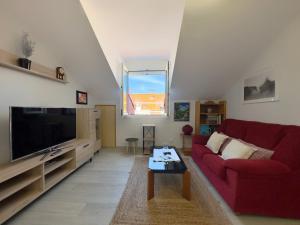 ein Wohnzimmer mit einem roten Sofa und einem TV in der Unterkunft El Alba - 30602 in Somo