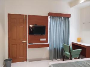 um quarto com uma cama, uma televisão e uma porta em Hotel Harshanaa Elite em Kanyakumari