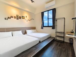 2 Betten in einem Zimmer mit Fenster in der Unterkunft Little Butler B&B in Huxi