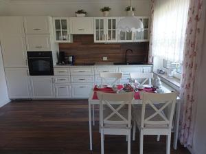 uma cozinha com uma mesa com armários brancos e cadeiras brancas em Ferienwohnung "Zwei Finken" in der Blumenstadt Wiesmoor em Wiesmoor
