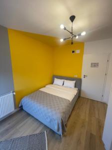 Cama en habitación con pared amarilla en Rooms, en Bacău