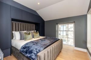 1 dormitorio con 1 cama grande y paredes azules en Dragon Suites - City Centre 2 Bed Luxury Mews House, en Edimburgo