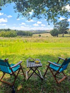 two chairs and a picnic table in a field at Kwaggaskop Farm Kliphuis in Dullstroom