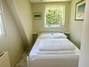 ein kleines Bett in einem Zimmer mit Fenster in der Unterkunft Duinland 31 in Sint Maartensvlotbrug