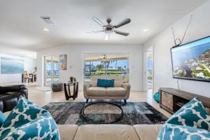 a living room with a couch and a tv at Amazing Water View with heated salt water pool - Villa Riverside - Roelens Vacations in Cape Coral