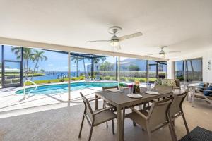 a dining room with a table and chairs and a pool at Amazing Water View with heated salt water pool - Villa Riverside - Roelens Vacations in Cape Coral