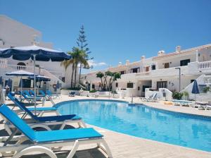a pool with chairs and umbrellas in a hotel at Sea view apartment in Los Cristianos in Arona
