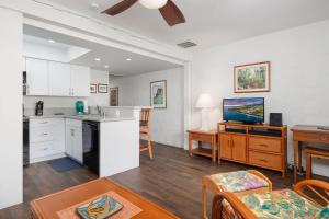 a kitchen and living room with white cabinets and a table at Casa De Emdeko 204 in Kailua-Kona