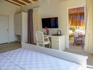 a room with a bed and a desk with a television at Oza Boutique hotel in Gümüşlük