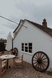 a white building with a table and chairs and an umbrella at The Fitzherbert Farmhouse in Swynnerton +31 photos