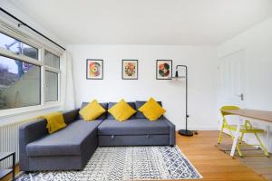 een woonkamer met een blauwe bank en gele kussens bij Beautiful 1BR Flat in The Heart of Croydon in Croydon