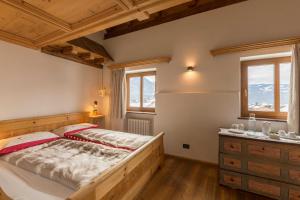 een slaapkamer met een bed, een dressoir en ramen bij Historic Hotel Ristorante La Stua in Cavalese
