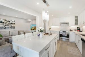 a white kitchen with a couch and a kitchen island at Pristine Pet & Smoke Free 4-Bedroom home near Canada's Wonderland in Vaughan