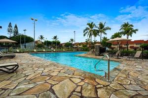 a swimming pool in a resort with chairs and palm trees at Keauhou Surf & Racquet Townhouse #36 in Kailua-Kona