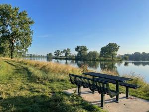 a park bench sitting next to a lake at Langs De Maas in Boxmeer