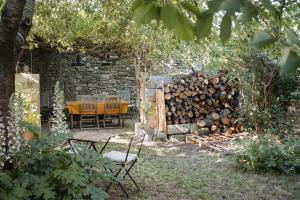 a table and chairs in a garden with a pile of logs at La Garrigue in Galargues