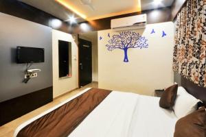 a bedroom with a bed with a tree and birds on the wall at Hotel Krishna Naroda in Ahmedabad