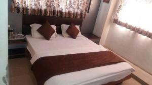 a bedroom with a bed with white sheets and pillows at Hotel Krishna Naroda in Ahmedabad