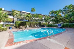 una piscina con palmeras y un edificio en Casa De Emdeko 211, en Kailua-Kona