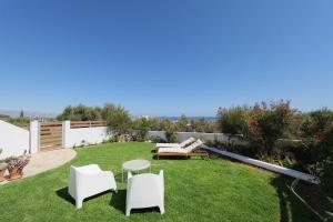 een tuin met witte stoelen en een tafel op het gras bij Sea you soon- Amazing Sea view in Achlia