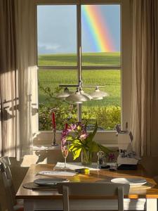 un arc-en-ciel vu à travers une fenêtre avec une table fleurie dans l'établissement Lavendel, à Am Schwarzen Busch