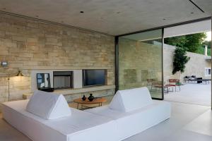 a living room with a white couch in front of a stone wall at Opsis villas, A waterfront & architectural retreat in Akrotiri