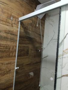 um chuveiro com uma porta de vidro e uma parede de madeira em Residencial Luce Del Sole - Casa Nº 5 em Joinville