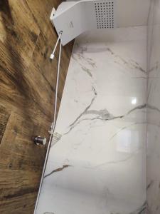 W łazience znajduje się prysznic i wyłożona białym marmurem podłoga. w obiekcie Residencial Luce Del Sole - Casa Nº 5 w mieście Joinville