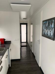 a kitchen with white walls and wooden floors and a hallway at EVASION in Nieuwpoort