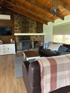 uma sala de estar com um sofá e uma lareira de pedra em Rustic Retreat: The Lodge Lurg Sanctuary em Upper Lurg