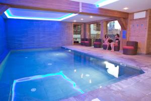 a swimming pool with two people sitting in chairs next to it at Chalet familial La Griotte avec piscine in Praz-sur-Arly