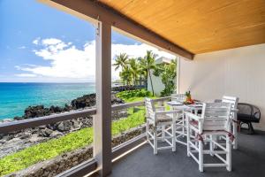 uma varanda com uma mesa e cadeiras e o oceano em Keauhou Kona Surf & Racquet Club #5-202 em Kailua-Kona