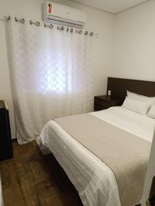 sypialnia z białym łóżkiem i oknem w obiekcie Residencial Luce Del Sole - Casa Nº 5 w mieście Joinville