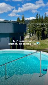 einem Pool mit blauem Wasser vor einem Gebäude in der Unterkunft SAVOIE Apartments Bukovel in Bukowel