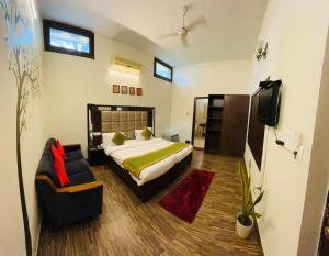 a bedroom with a bed and a tv and a couch at Capital O 3695 Hotel Daichi in Dehradun