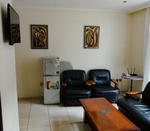 een woonkamer met 2 leren stoelen en een koelkast bij Nobilis Hotel and Apartments in Kigali
