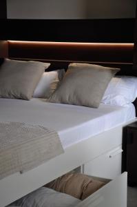 Cama blanca con sábanas y almohadas blancas en Camping Fonts del Algar, en Callosa de Ensarriá