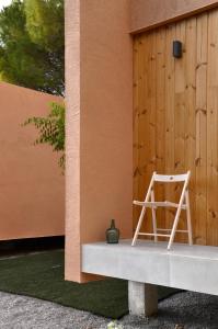 uma cadeira sentada num banco ao lado de um edifício em Camping Fonts del Algar em Callosa de Ensarriá
