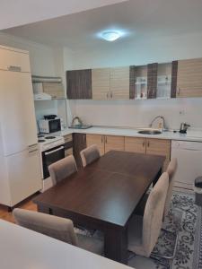 cocina con mesa de madera con sillas y nevera en Doboj Apartman, en Doboj