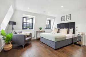 a bedroom with a large bed and a chair at 3BR Penthouse with Terrace - CityApartmentStay in London