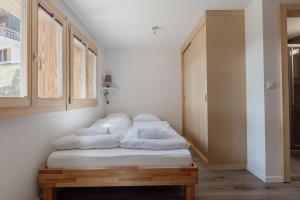 um quarto com uma cama com lençóis brancos em Charmant studio rénové à Grimentz em Grimentz