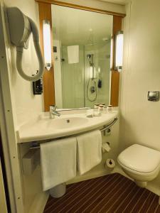 uma casa de banho com um lavatório, um WC e um espelho. em Ibis Lugano Paradiso em Lugano
